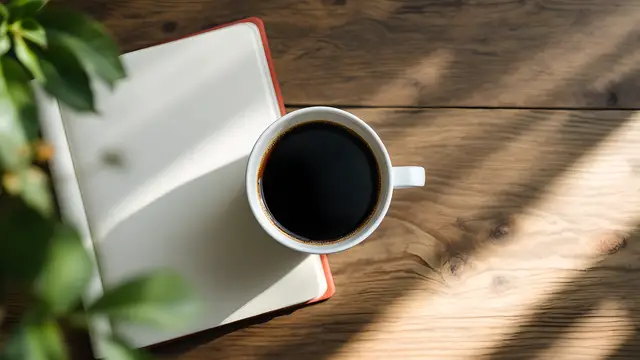 A coffee cup and open notebook on a wooden desk