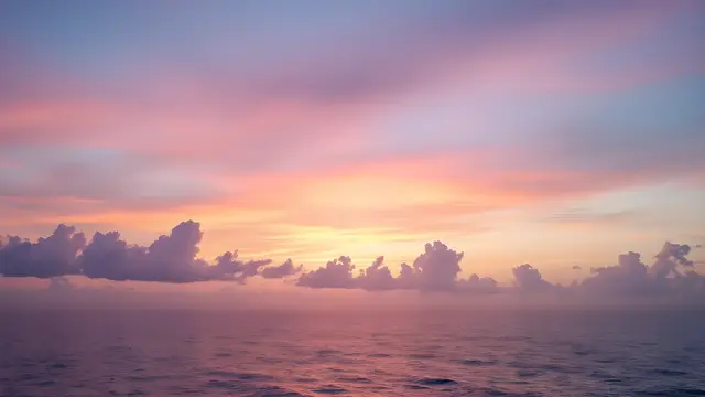 Pastel pink and lilac clouds at sunset over a calm sea