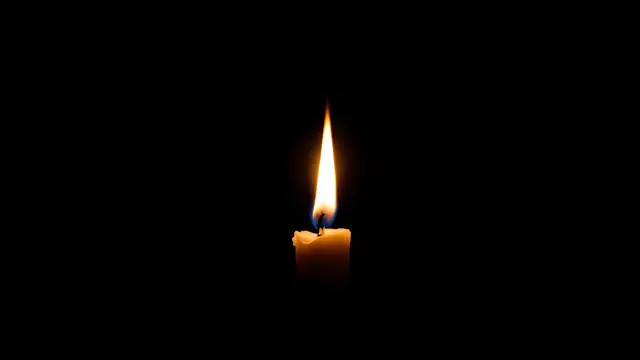 A small candle flame glowing in darkness