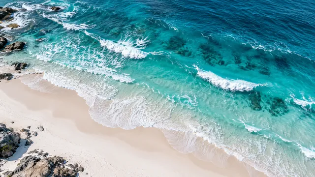 Turquoise ocean waves rolling onto a white beach