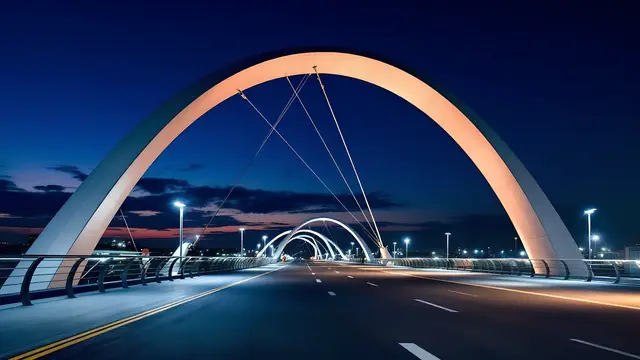 A curved modern bridge at dusk with soft ambient light