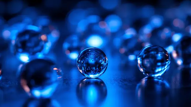 Clear glass spheres on a reflective dark surface, cool blue light