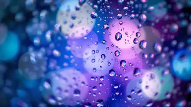 Water droplets on glass with soft blue and violet lights behind