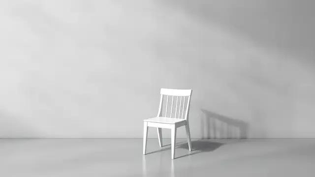 A single white chair against a plain concrete wall