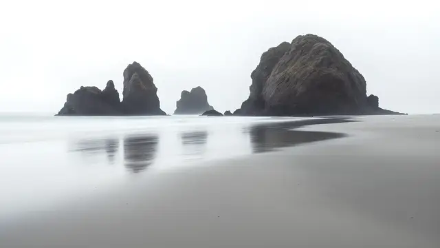A calm beach with a single set of rock formations