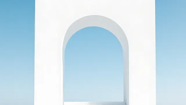 A white arched wall opening onto a clear blue sky