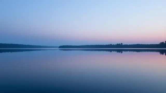 A still lake mirroring a plain sky at dusk