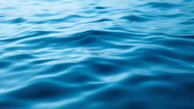 A still water surface with gentle ripples in cool blue tones