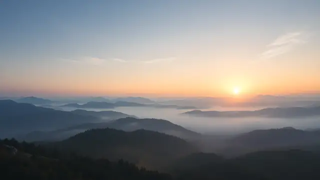 A sunrise over misty mountains, wide open sky