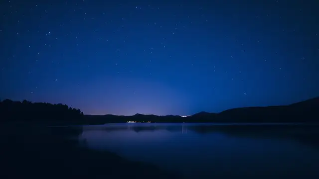 A clear night sky full of stars over a quiet lake