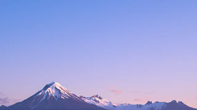 A snow-capped mountain peak against a clear blue sky