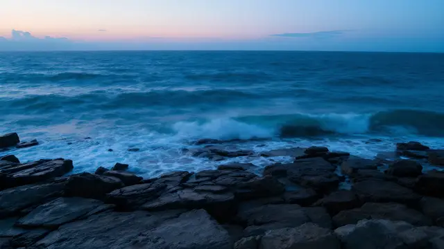 Ocean waves breaking on a rocky shore at dusk
