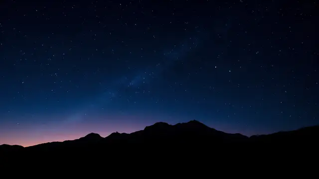 A starry night sky over a silhouetted mountain range